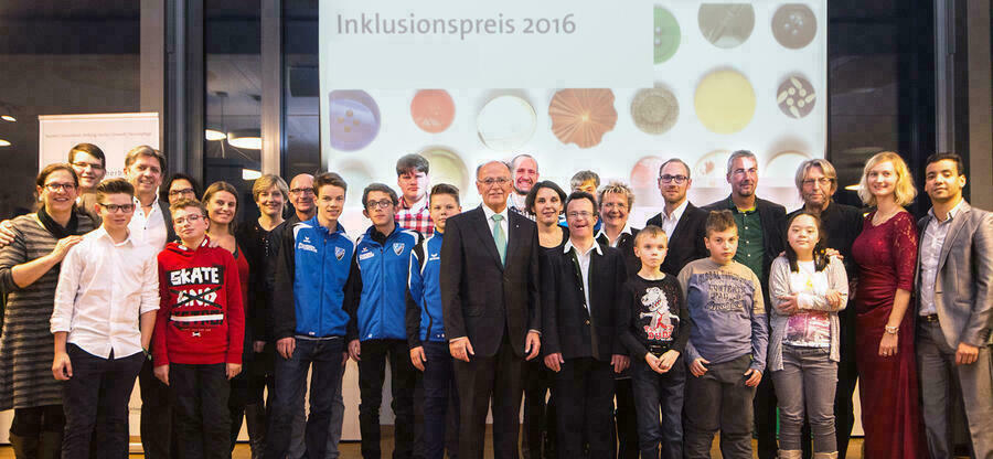 Gruppenfoto mit KIndern, Jugendlichen und Erwachsenen vor einer Projektionsleinwand mit Schriftzug  "Inklusionspreis 2016" und Logo. In der Mitte Bezirkstagspräsident Josef Mederer.