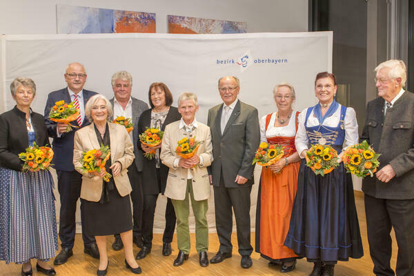 Gruppenfoto mit zehn Personen. Bis auf den Bezirkstagspräsidenten halten alle einen Blumenstrauß in den Händen.