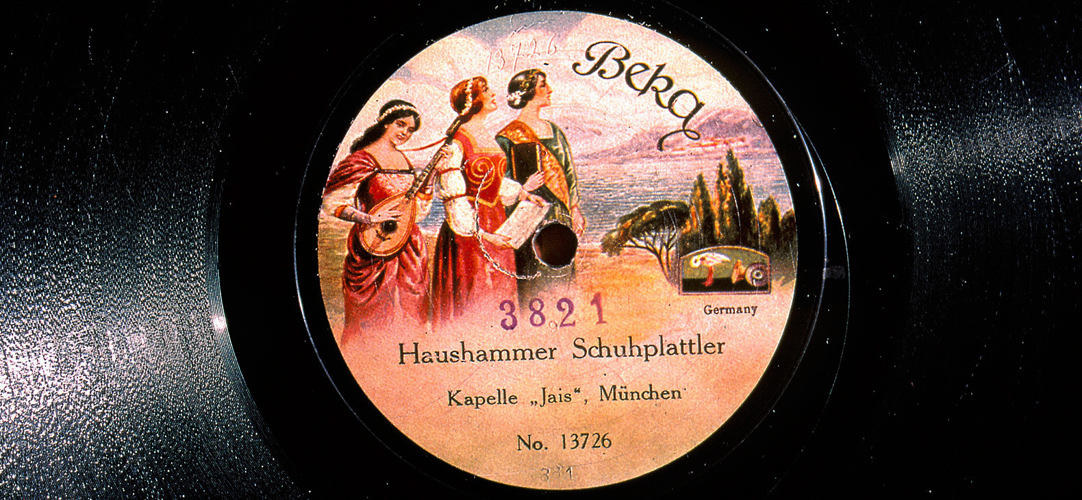 Eine Schallplatte: Auf dem Etikett ist ein Gemälde mit drei Frauen in Gewändern vor einer südeuropäischen Landschaft zu sehen und man kann "Haushammer Schuhplattler" und "Kapelle 'Jais'" sowie das Label "Beka" lesen.