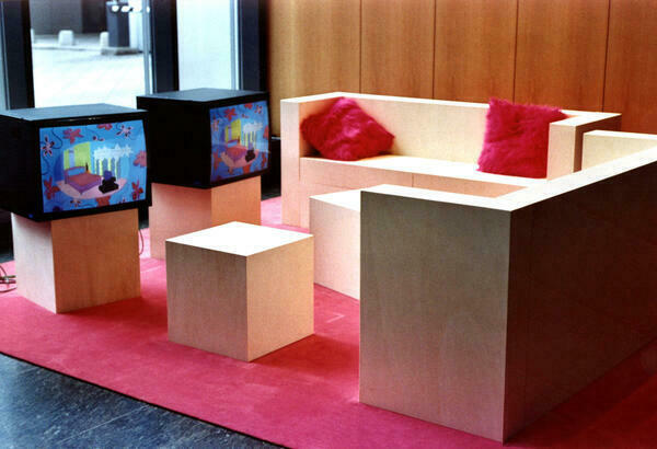 Sitzecke mit Möbeln aus Holz sowie mehreren Kissen und einem Fussboden aus rosa Material