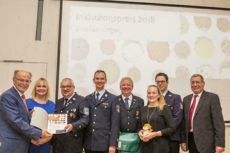 Gruppenfoto mit mehreren Feuerwehrleuten in Ausgehuniform und Bezirksräten. Links Bezirkstagspräsident Josef Mederer.