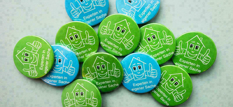 Buttons in blauer und grüner Farbe mit Aufschrift: "So will ich leben und wohnen"