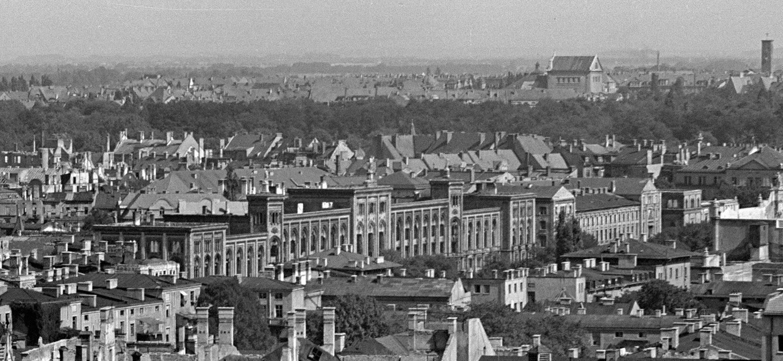 Schwarz-Weiß-Aufnahme: Blick über Münchner Stadtteil Lehel in der Nachkriegszeit. Zentral ist der damalige Sitz des Bezirks Oberbayern zu sehen.
