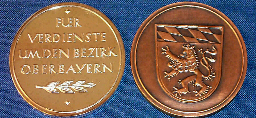 Beide Seiten der Medaille sind nebeneinander zu sehen; auf einer Seite steht der Text "Für Verdienste um Oberbayern", auf der anderen Seite ist das Wappen von Oberbayern eingraviert.