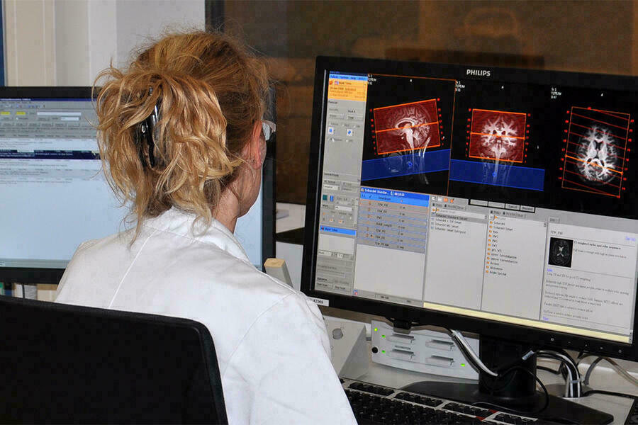 Frau schaut in Computer mit Aufnahmen eines Kopfes