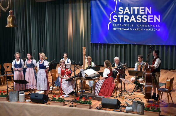 Musikbühne mit zehn Musikerinnen und Musikern in traditionellen bayerischen Trachtenkleidern