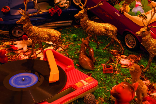 Auf dem Foto sieht man unter anderem einen roten Kinder-Plattenspieler, Moos, Blätter und goldene Plastikhirsche.