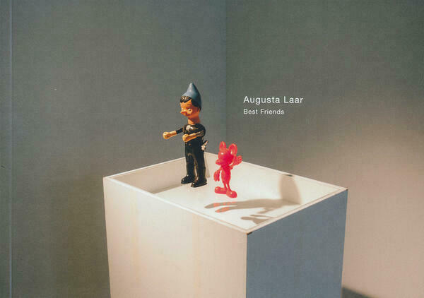 Buchcover des Ausstellungskataloges von Augusta Laar:
Eine Zwergenfigur und eine rote Micky Maus stehen auf einer Glasplatte einer Vitrine und scheinen zu schweben.