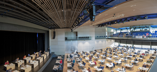 Blick von oben in eine große Konferenz-Raum, in dem an vielen  einzelnen Tischen Bezirksräte sitzen