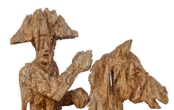 Skulptur aus Holz: Reiter auf Pferd. die Skulptur ist aus groben Schnitten mit der Motorsäge geformt.