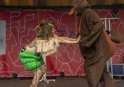 Zwei Schauspieler; einer in einem Bärenkostüm, einer als Mowgli verkleidet, stehen zusammen auf einer Bühne