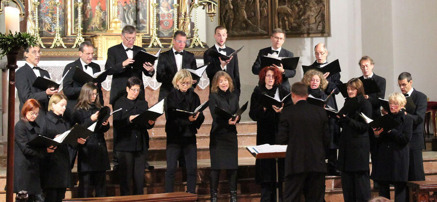Heinrich-Schütz-Ensemble Freising; Bild: schwarz gekleidete Sängerinnen und Sänger auf der Bühne in zwei Reihen mit Dirigenten