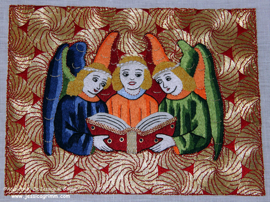 Ein gesticktes Bild zeigt drei Engel, die in einem Buch lesen. Um sie herum befinden sich aus Goldfäden gestickte Spiralen.