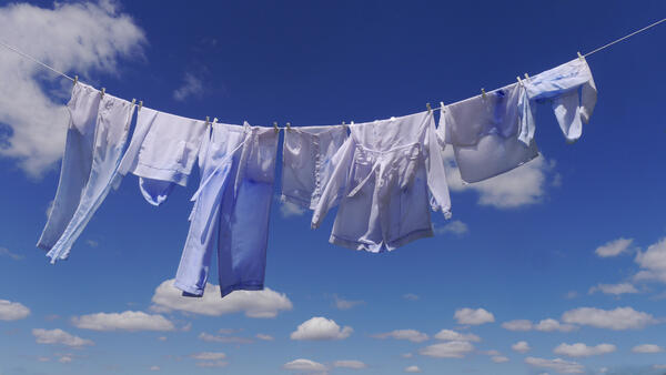 Kunstwerk: Fotografie einer Wäscheleine mit Wäschestücken, die die gleiche Färbung aufweisen wie der weiß-blaue Himmel im Hintergrund