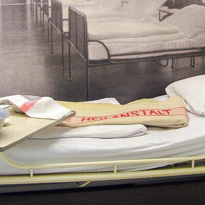 Krankenhausbett aus den 50er Jahren mit Decke und Beistelltisch
