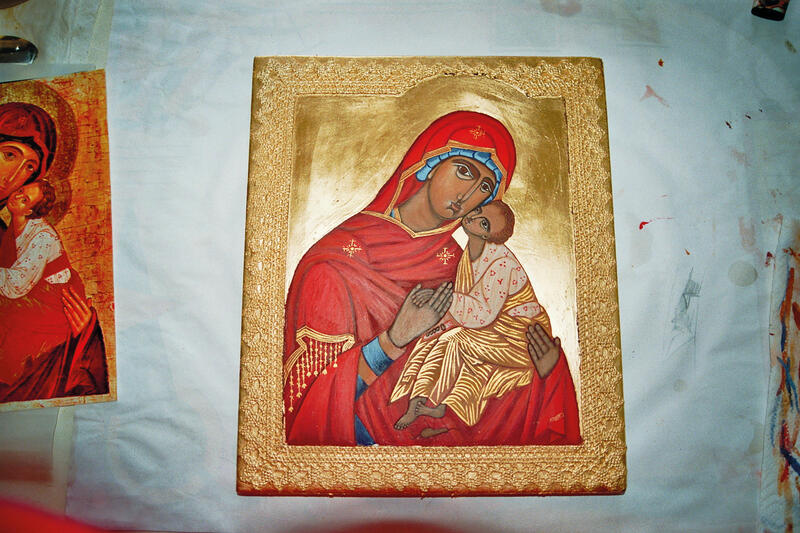 Bild einer Ikone mit goldenem verzierten Rahmen: Es zeigt auf goldenem Grund eine rotgewandete Mutter Gottes mit dem Kind (weiß-goldenes Kleid) im Arm.