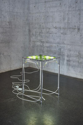Tisch aus Metall mit von unten beleuchteter Galsfläche in weiß-grünen Karos.