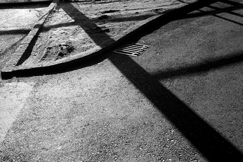 Schwarz-Weiss-Fotografie: Schatten und Begrenzungssteine bilden ein abstraktes Linienmuster