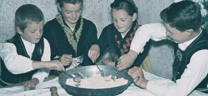 Historisches Foto in verblichenen Farben aus den fünfziger Jahren: Vier Kinder beim Auslöffeln der eingebrockten Suppe.