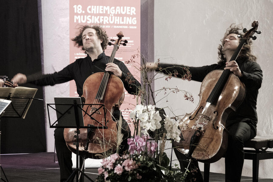 Zwei Männer Spielen auf einer Bühne Kontrabass und zwischen ihnen sind Blumen zu sehen.