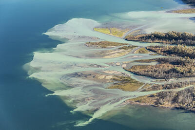 Flussdelta ergiesst sich in einen See. Die Wasserfarbe wechselt von Hell-Türkis ins Dunkel-Blau