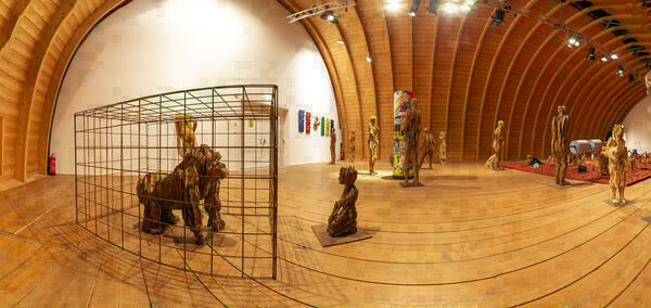 Panoramafoto der Ausstellungssituation im Tonnengewölbe von Schafhof - europäisches Künstlerhaus Oberbayern: Im Raum verteilt sieht man verschiedene große Holzskulpturen.