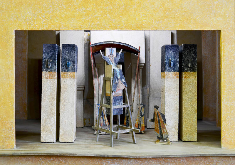 Foto eines Bühnenmodells. Säulenartige  Architektur mit farbig abgestzten Flächen, kleine Figuren stellen Pharisäer dar, der hohe Priester sitzt af einer Art Hochsitz