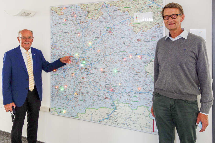 Bezirkstagspräsident Mederer (links)  und Leiter der Leitstelle, Dr. Michael Weschehold stehen vor einer Karte mit den Standorten der mobilen Einsatzteams in Oberbayern.