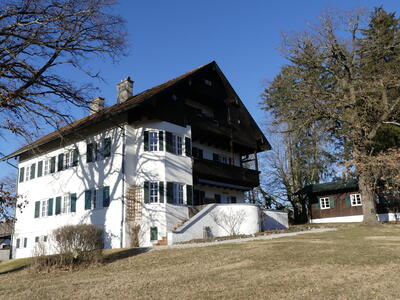 Dreigeschossiges historisches Anwesen mit Holzgiebel, Holzbalkon und Erker an einem Hang
